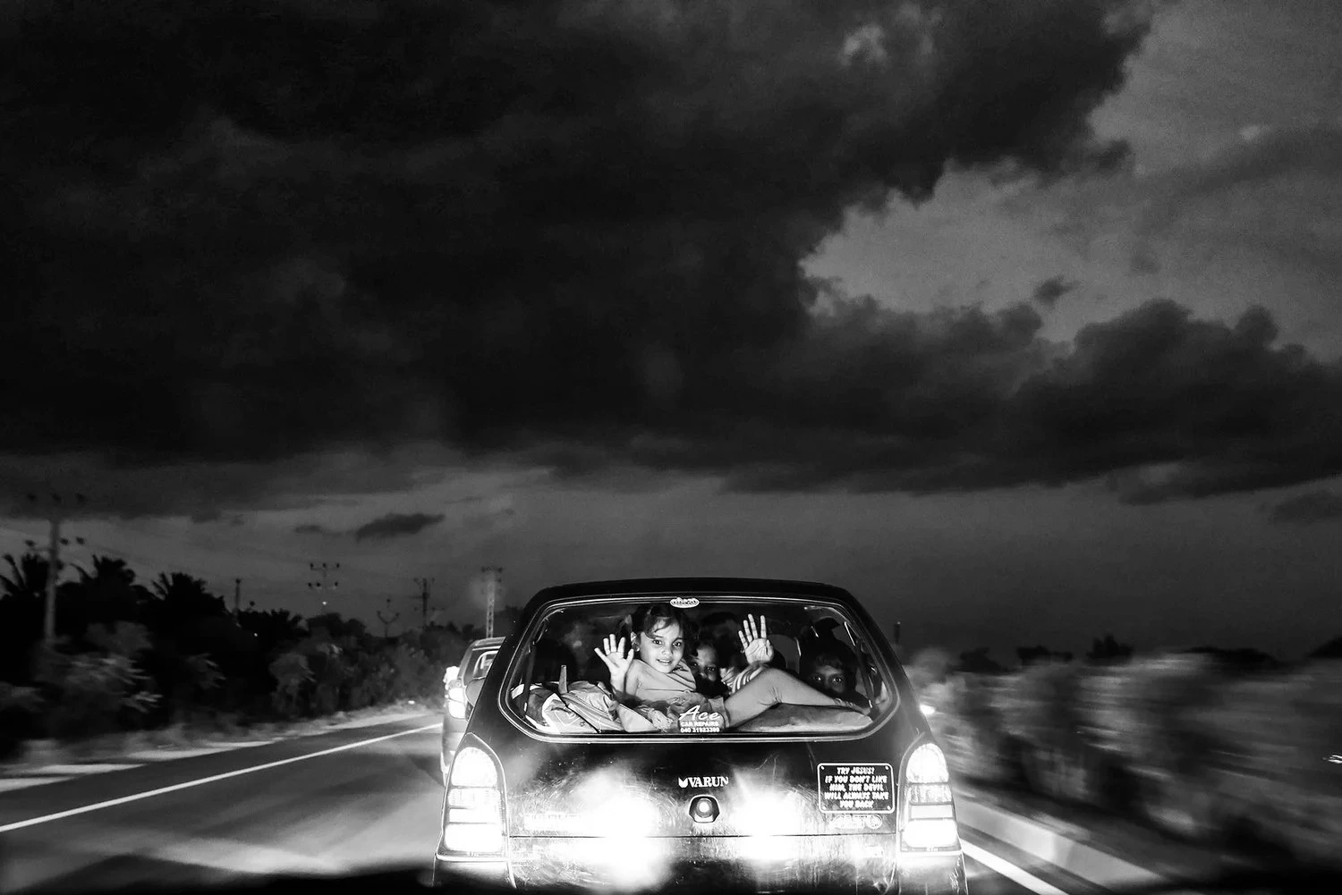 Crno-bijela dokumentarna fotografija djece koja se voze u otvorenom prtljažniku automobila, serija Binary - Duality of Being, reFocus Awards 2026