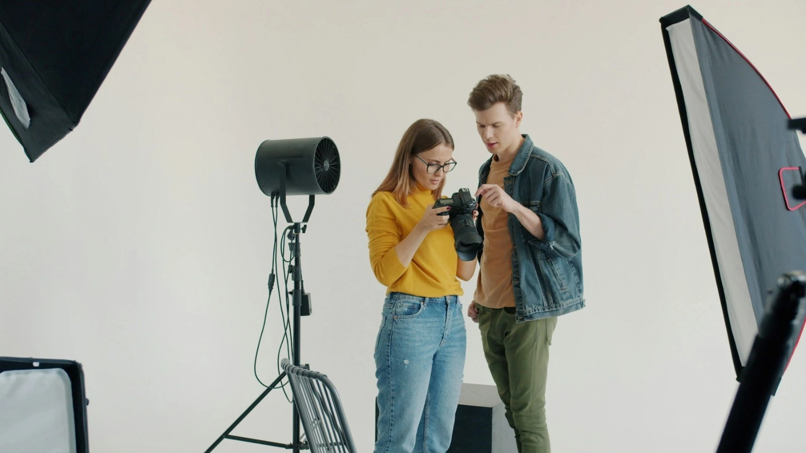Fotograf i model gledaju snimku na ekranu fotoaparata u studiju