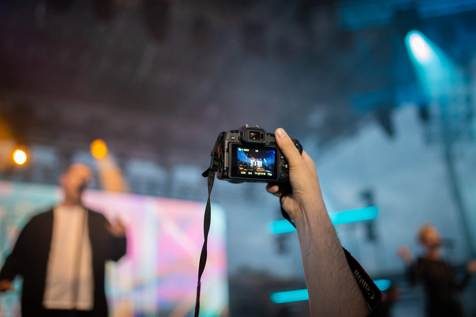 Posjetitelj podiže fotoaparat iznad publike i snima pozornicu